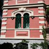 ...presenta raffinate finestre monofore e bifore con persiane e imposte verdi...